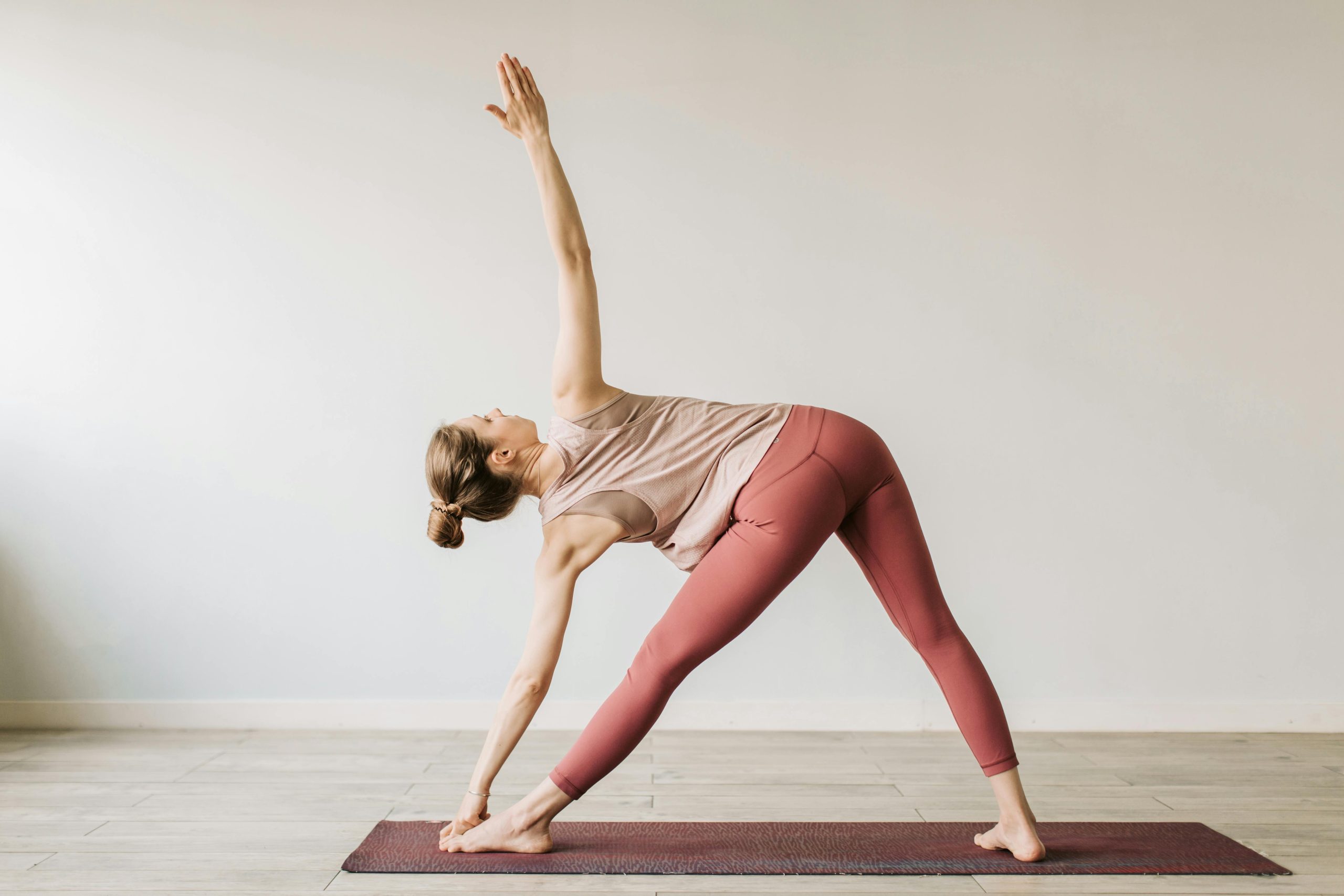 A woman performing the yoga triangle pose indoors, showcasing flexibility and wellness.
